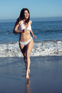 Kira in bathing suit running along the beach